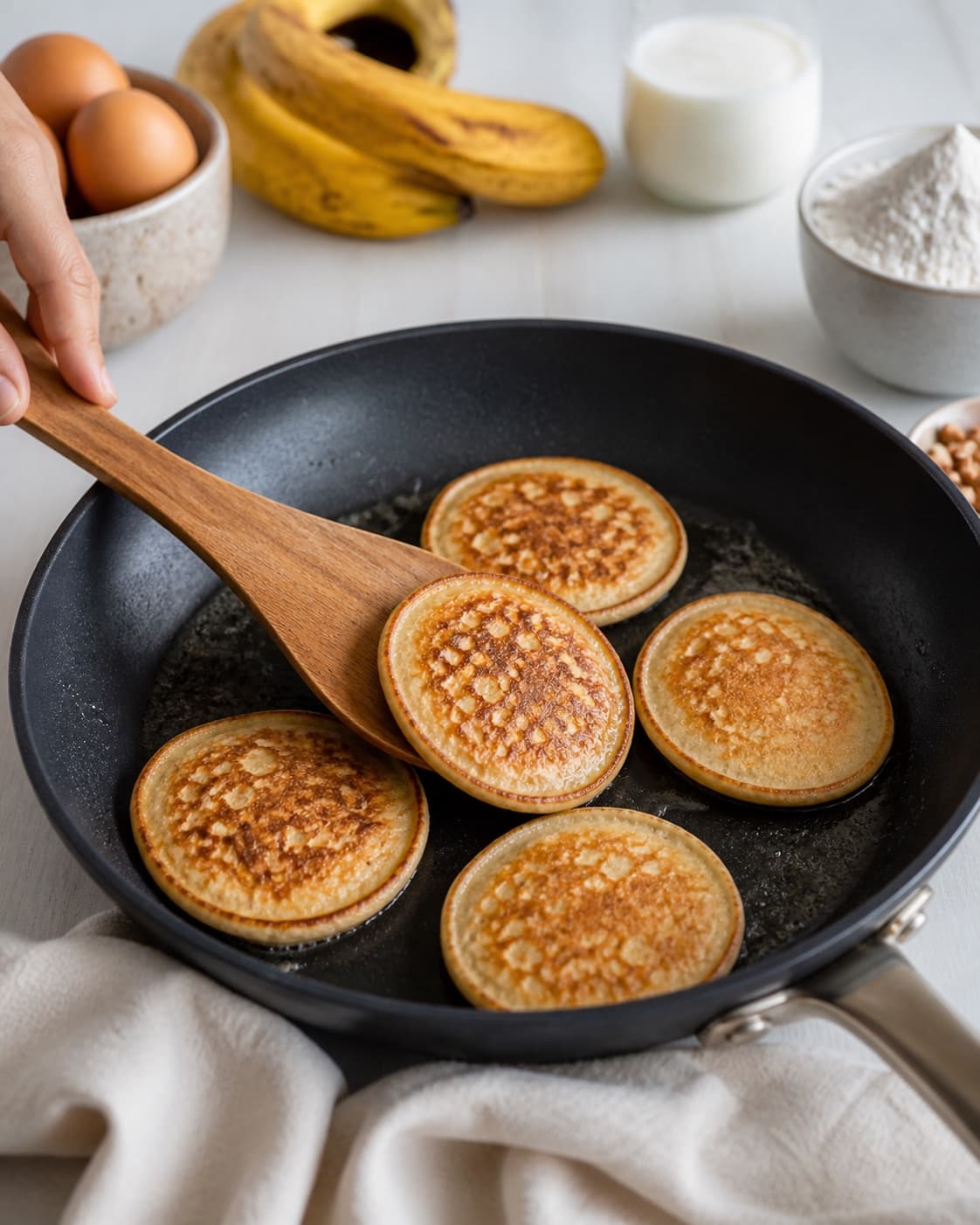bananpandekager frying to an even golden crust in a pan under tilberedningen af bananpandekager