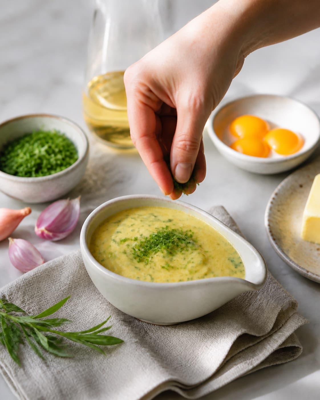 Fresh finished bearnaise sauce receiving its final garnish under tilberedningen af bearnaise sauce