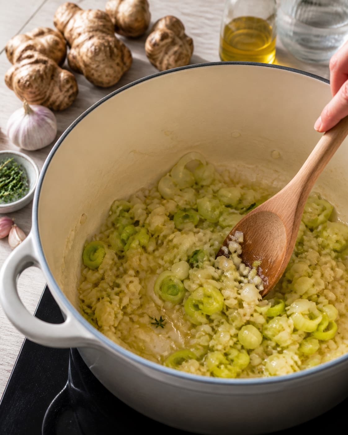 Aromatic base for jordskokkesuppe med urteolie gently cooking in a pot under tilberedningen af jordskokkesuppe med urteolie