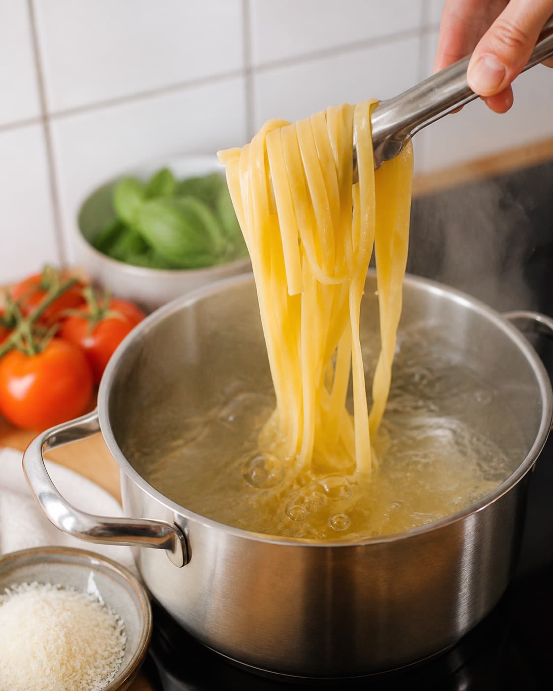 Pasta for italienske kødboller i tomatsauce med pasta being lifted from boiling water under tilberedningen af italienske kødboller i tomatsauce med pasta