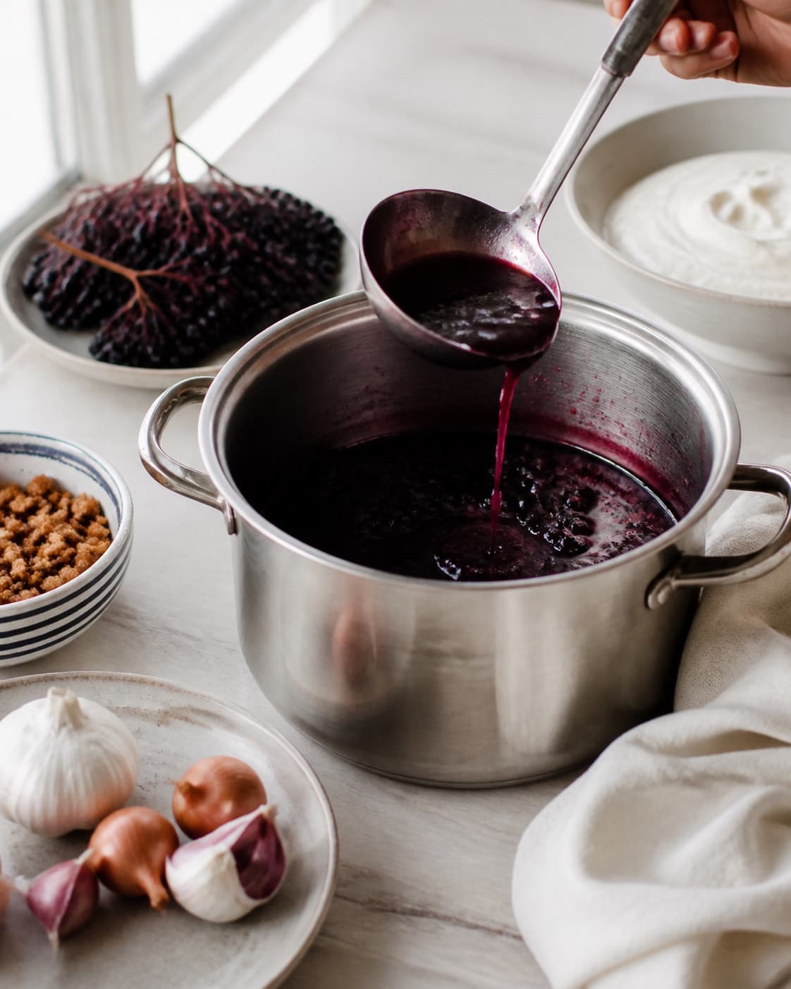 Mise en place for hyldebærsuppe med flødeskum og knas with hyldebær, piskefløde, zittauerløg, hvidløg under tilberedningen af hyldebærsuppe med flødeskum og knas