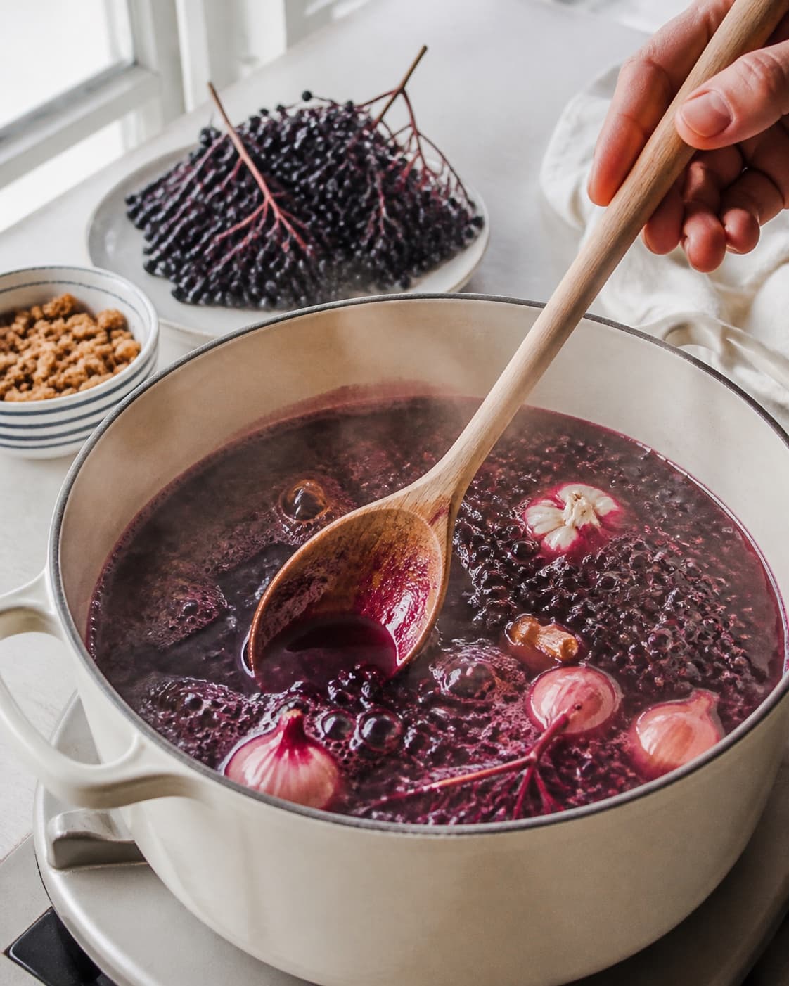 hyldebærsuppe med flødeskum og knas gently simmering with visible ingredients under tilberedningen af hyldebærsuppe med flødeskum og knas