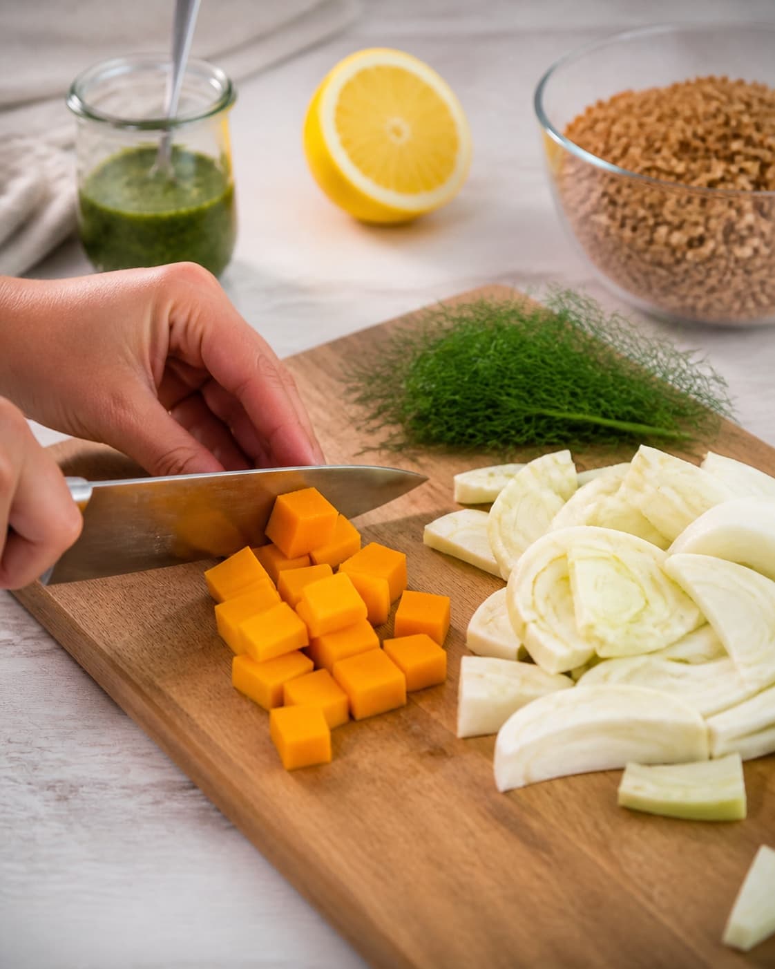 Ingredients for hvedekernesalat med græskar og urteolie being cut into even pieces under tilberedningen af hvedekernesalat med græskar og urteolie