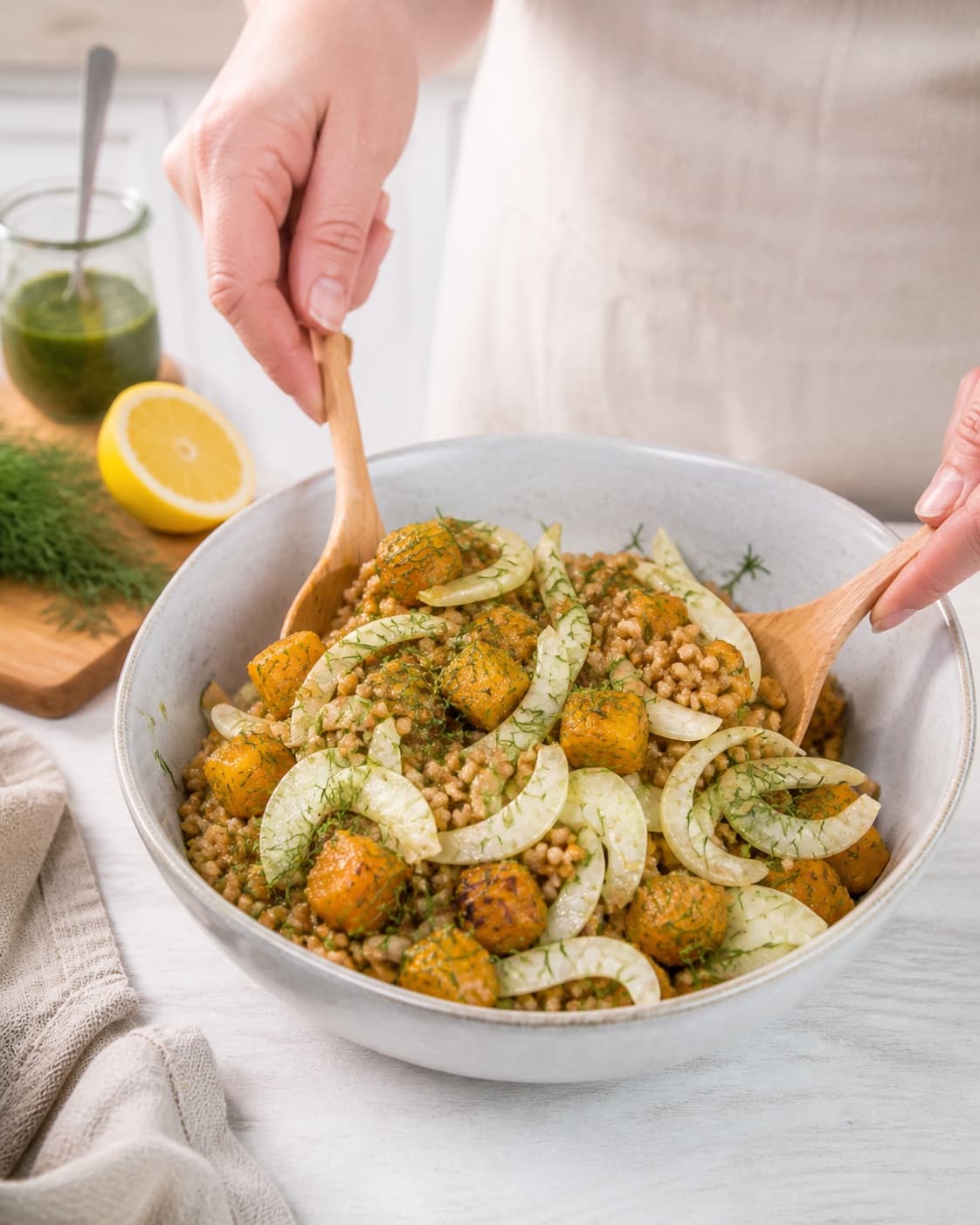hvedekernesalat med græskar og urteolie being gently combined without crushing the ingredients under tilberedningen af hvedekernesalat med græskar og urteolie