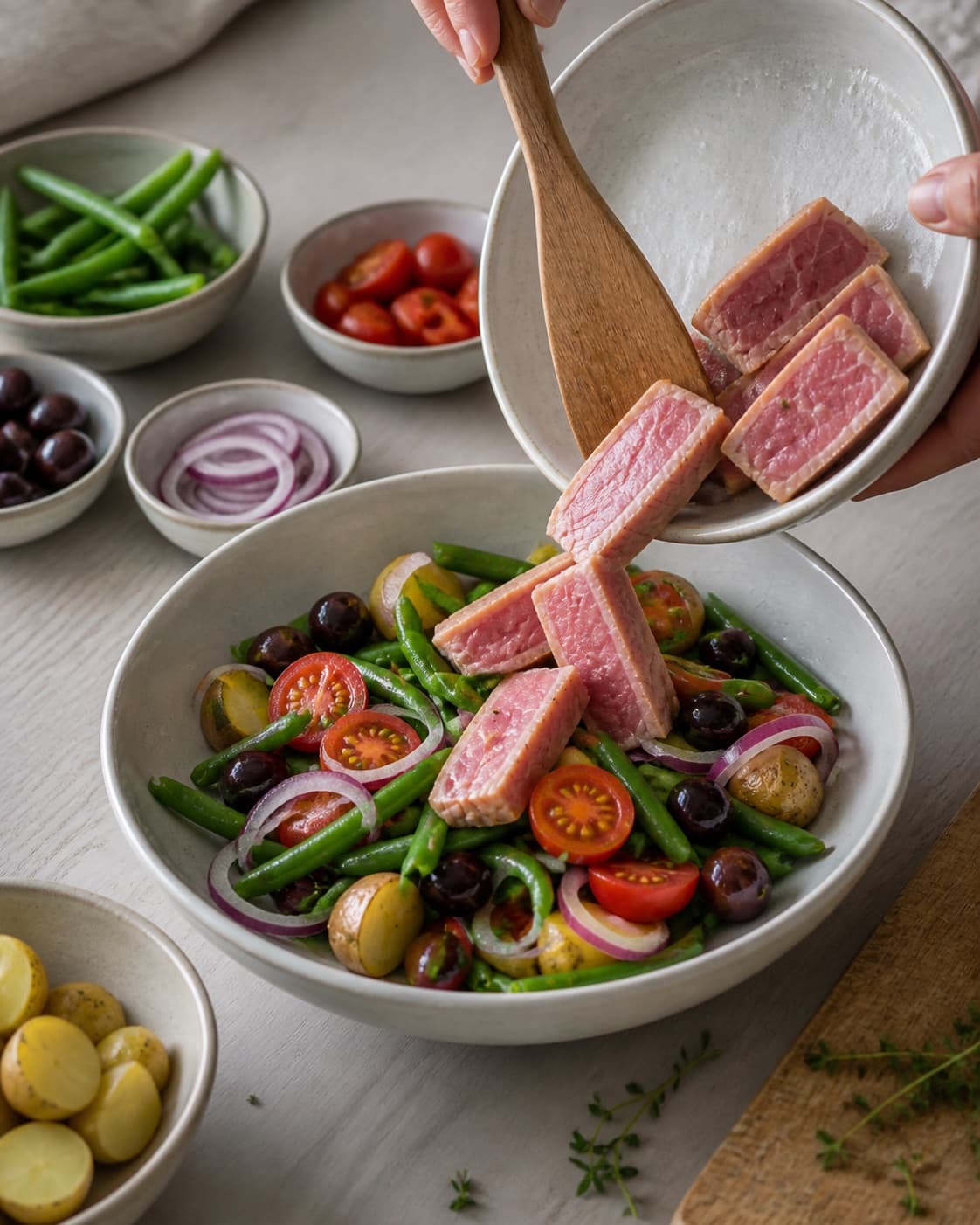 Mise en place for salade nicoise with tun i olivenolie, grønne bønner, sorte oliven, zittauerløg under tilberedningen af salade nicoise
