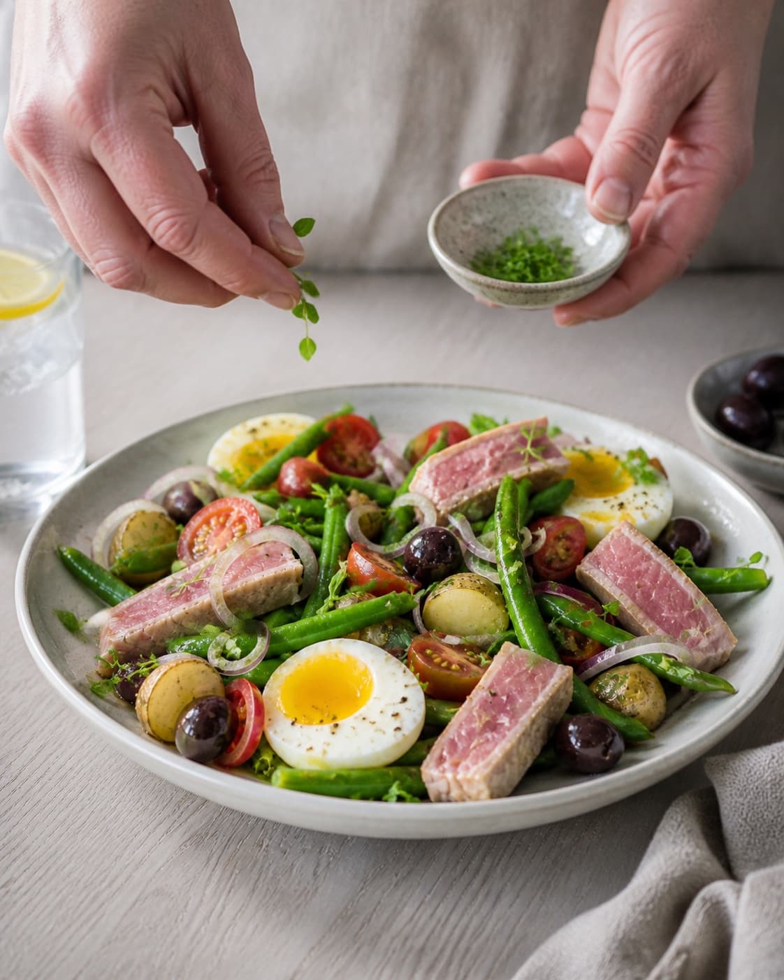Finished salade nicoise being served with a fresh restrained garnish under tilberedningen af salade nicoise