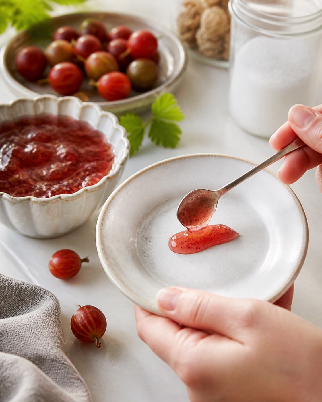 A chilled consistency test for stikkelsbærmarmelade on a small plate under tilberedningen af stikkelsbærmarmelade