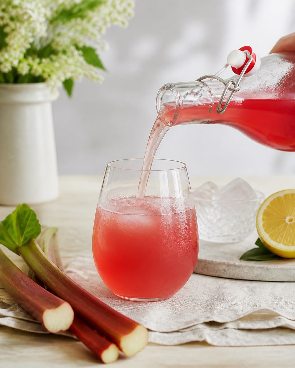 Finished rabarbersaft being poured into a clean serving glass under tilberedningen af rabarbersaft