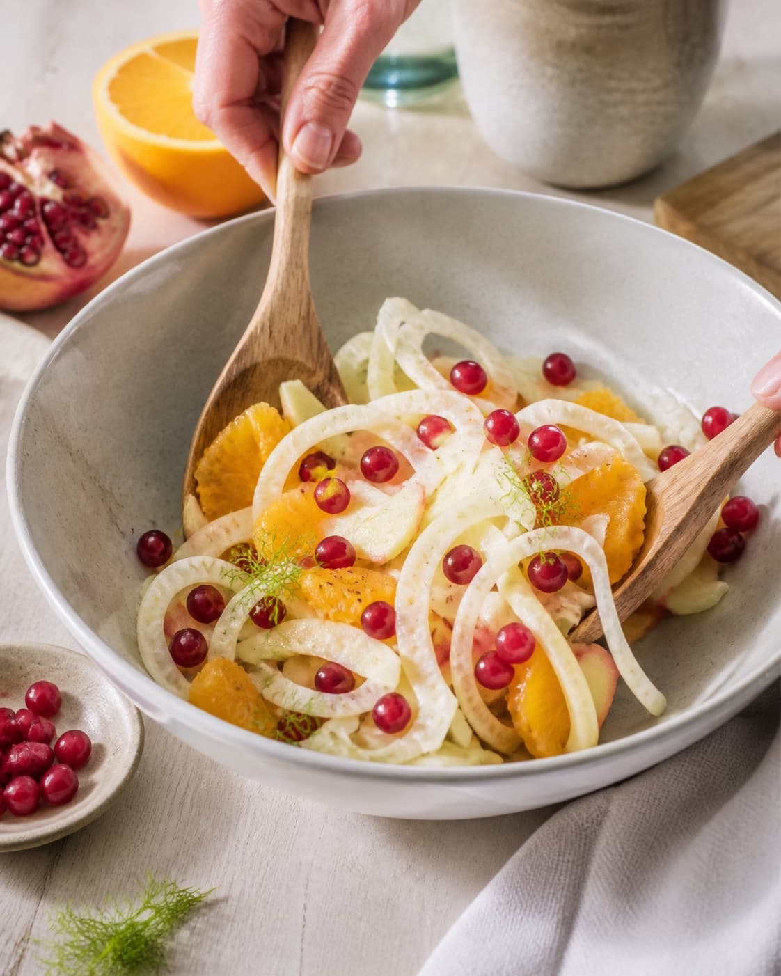 fennikelsalat med appelsin og granatæble being gently combined without crushing the ingredients under tilberedningen af fennikelsalat med appelsin og granatæble