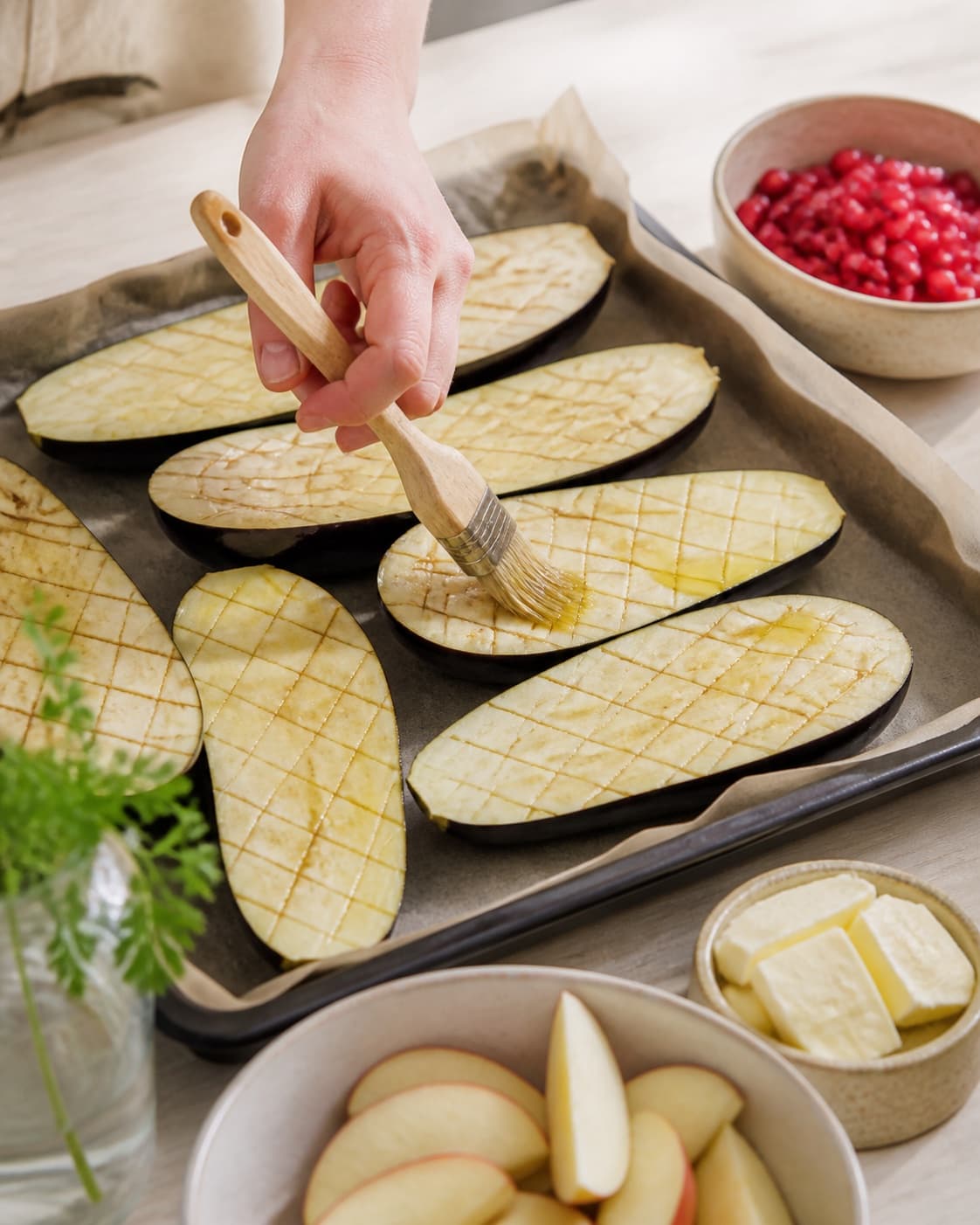 Prepared dry ingredients for bagte auberginer med tahin og granatæble with auberginer, syrlige æbler, granatæblekerner, smør under tilberedningen af bagte auberginer med tahin og granatæble