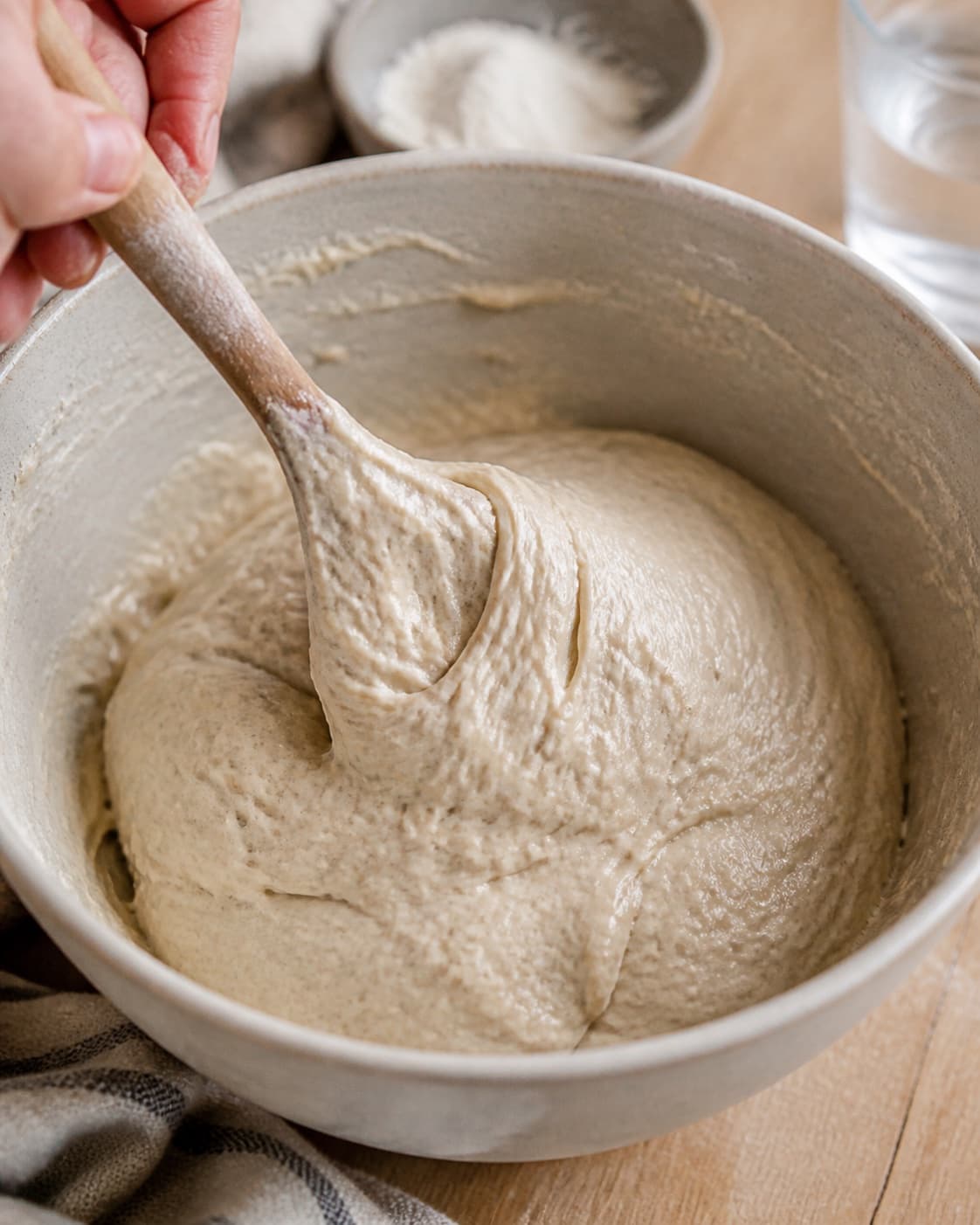 Close view of the moist dough for toastbrød – bagt med surdej being mixed in a bowl with aktiv surdej, hvedemel, lunkent vand, gær under tilberedningen af toastbrød – bagt med surdej