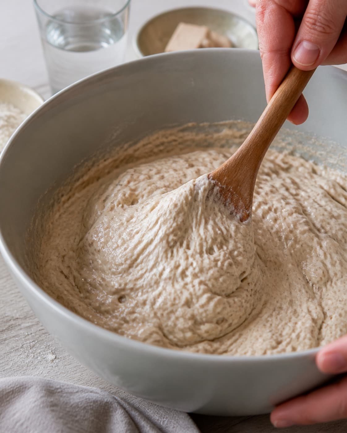 Close view of the moist dough for brusebadsboller being mixed in a bowl with koldhævet dej, hvedemel, lunkent vand, gær under tilberedningen af brusebadsboller