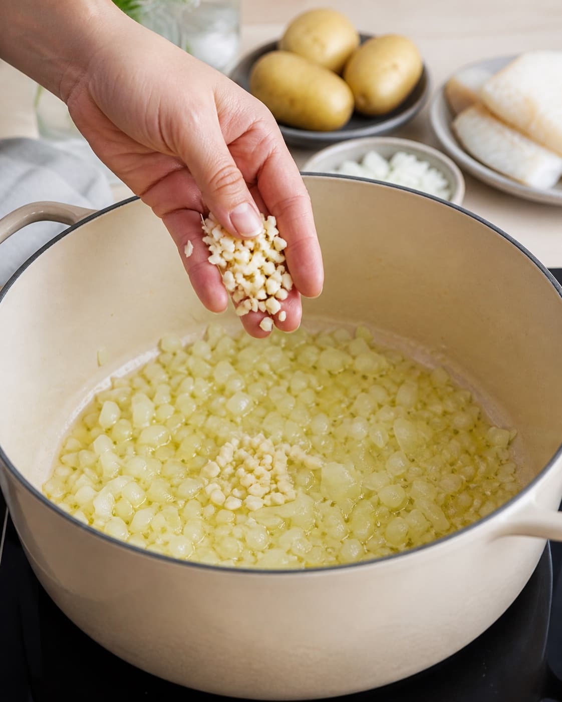 Aromatic base for brandade med torsk gently cooking in a pot under tilberedningen af brandade med torsk