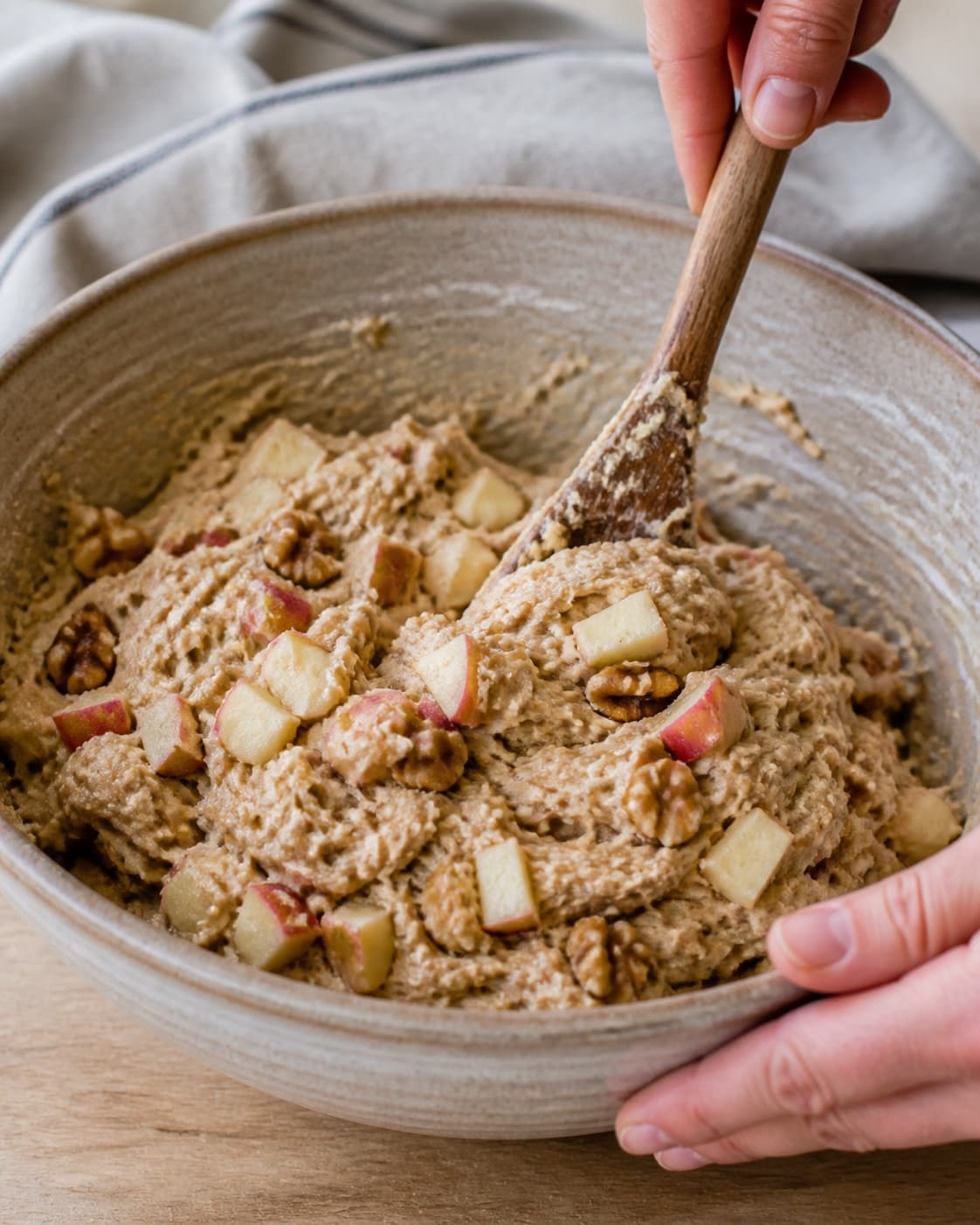 Close view of the moist dough for æbleboller med nødder being mixed in a bowl with valnødder, syrlige æbler, hvedemel, lunkent vand under tilberedningen af æbleboller med nødder