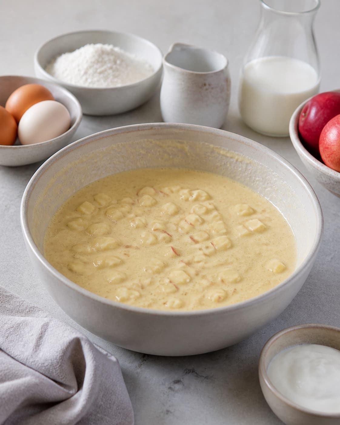 Prepared mixture for æblepandekager with æg, syrlige æbler, hvedemel, mælk under tilberedningen af æblepandekager