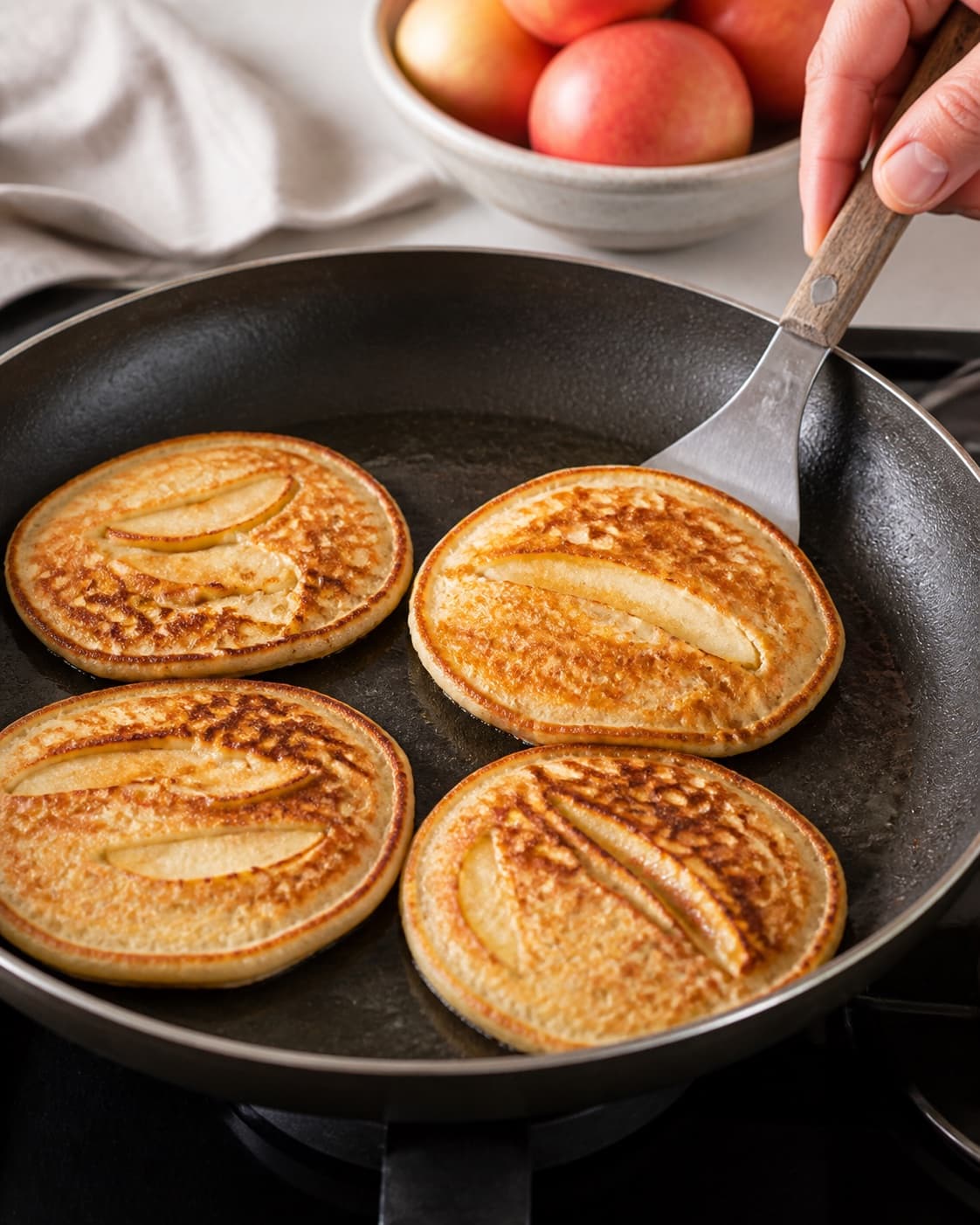 æblepandekager frying to an even golden crust in a pan under tilberedningen af æblepandekager