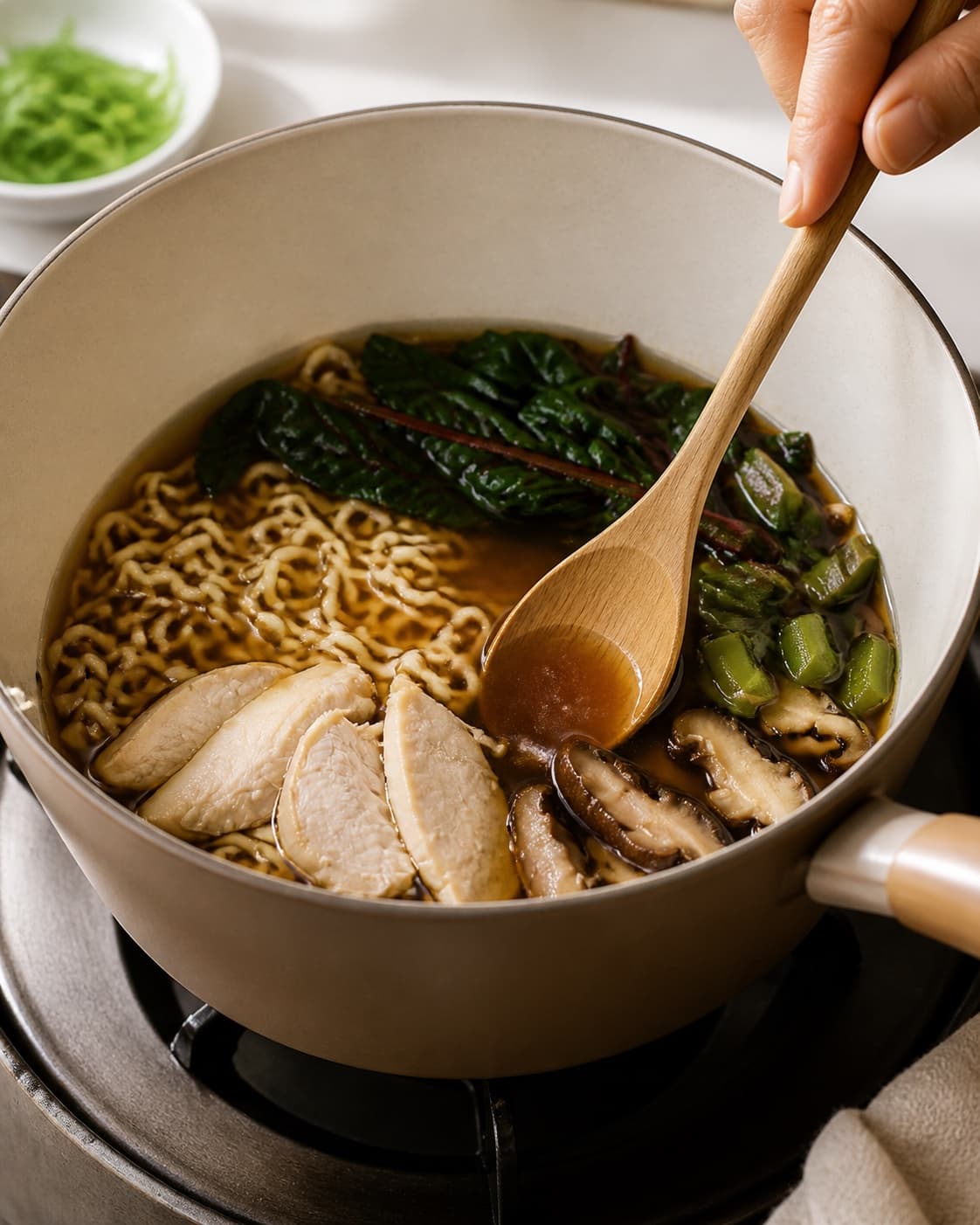 The texture of ramen suppe med kylling og nudler being adjusted in the pot under tilberedningen af ramen suppe med kylling og nudler
