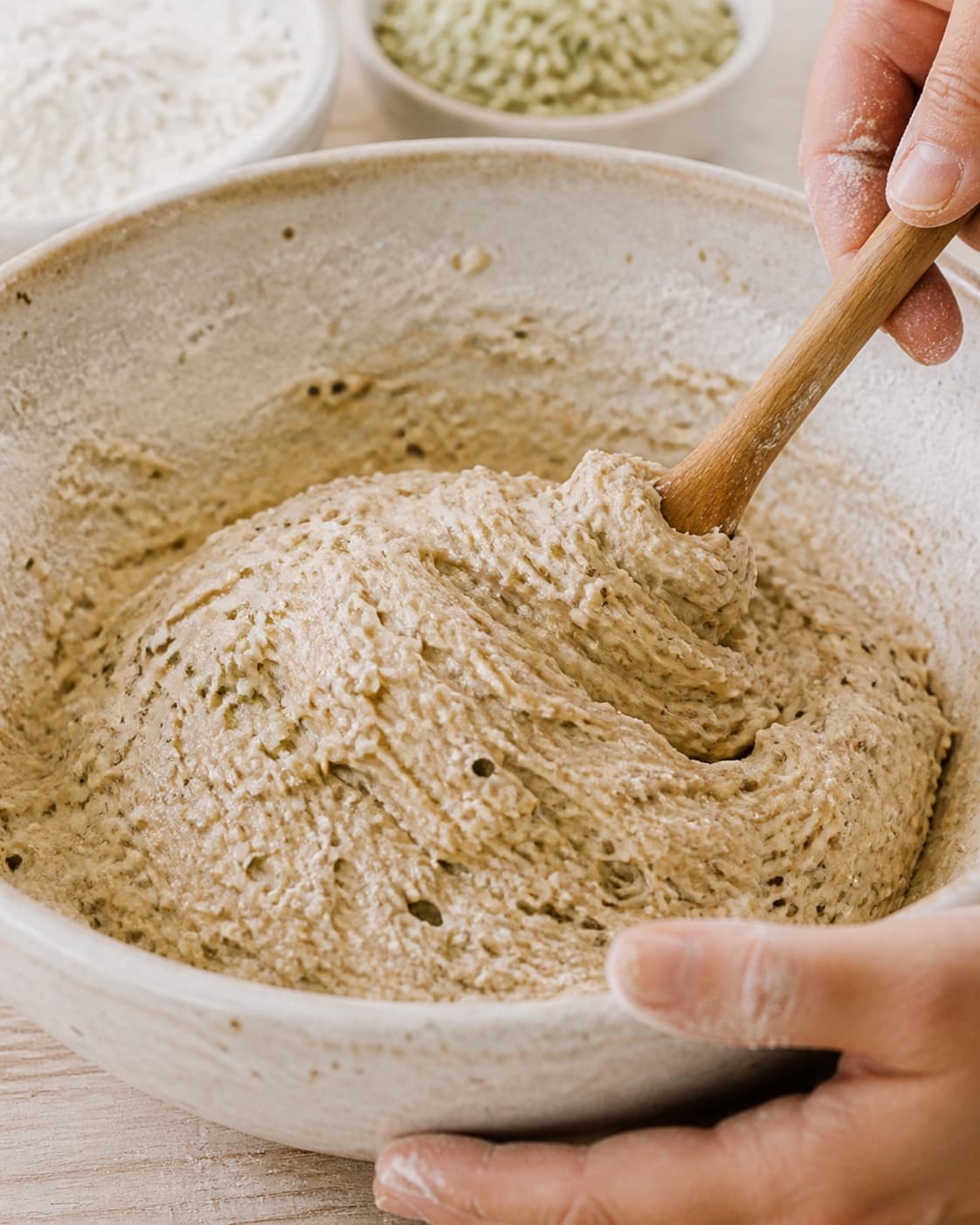Close view of the moist dough for boller med hampefrø being mixed in a bowl with hampefrø, hvedemel, lunkent vand, gær under tilberedningen af boller med hampefrø