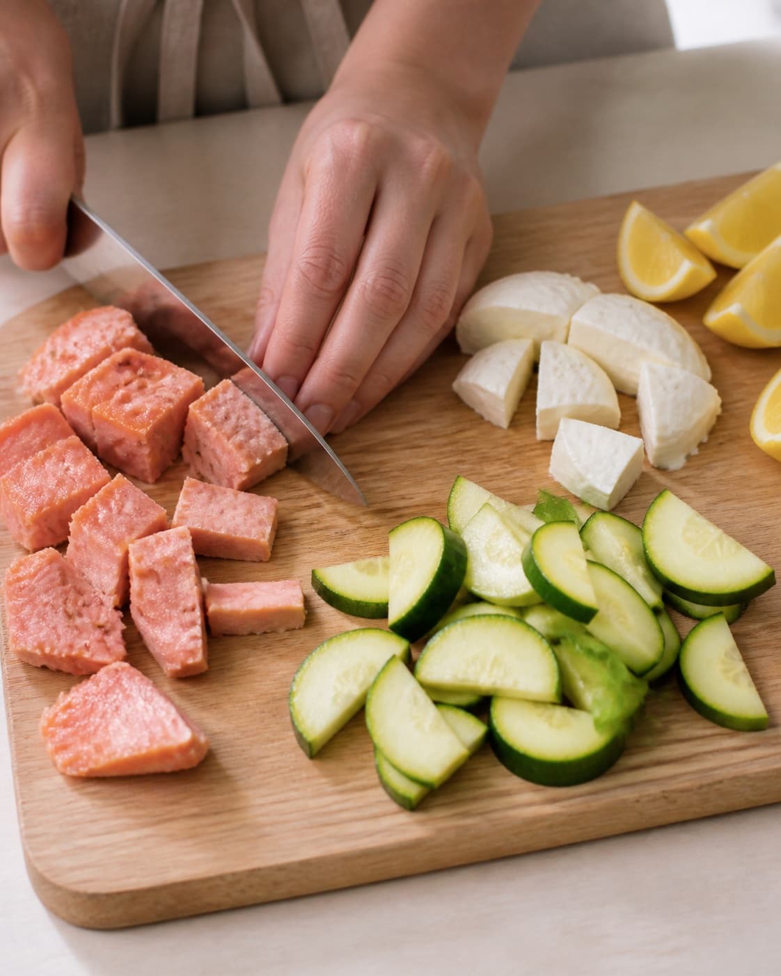 Ingredients for varmrøget laks med rygeostcreme og squashsalat being cut into even pieces under tilberedningen af varmrøget laks med rygeostcreme og squashsalat