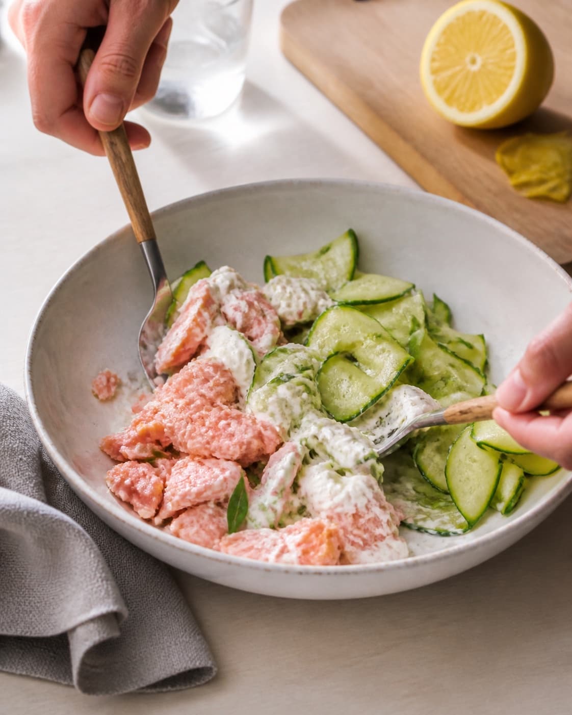 varmrøget laks med rygeostcreme og squashsalat being gently combined without crushing the ingredients under tilberedningen af varmrøget laks med rygeostcreme og squashsalat