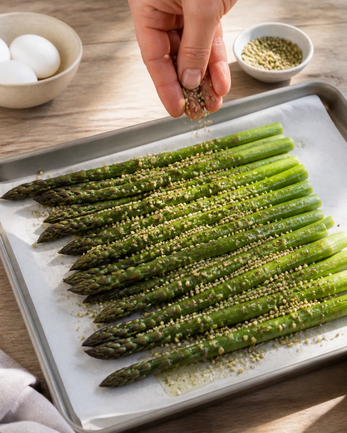 grillede asparges med pocheret æg og ristede hampefrø being evenly seasoned before roasting under tilberedningen af grillede asparges med pocheret æg og ristede hampefrø