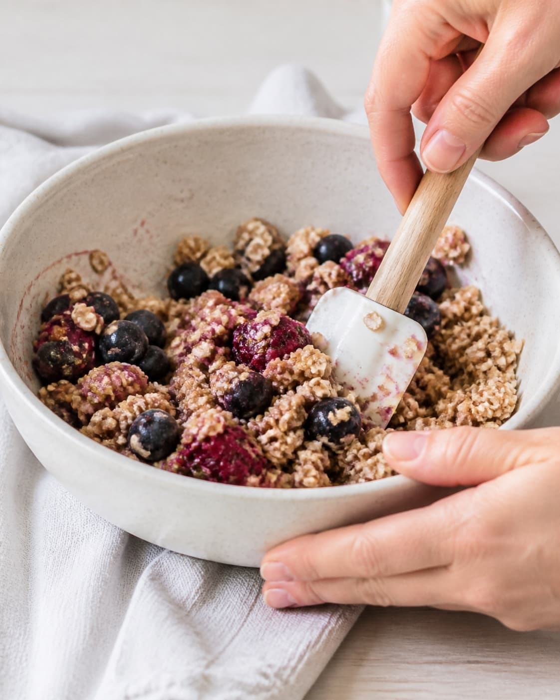 The batter or dough for crumble med bær og havregryn til morgenmad being gently combined under tilberedningen af crumble med bær og havregryn til morgenmad