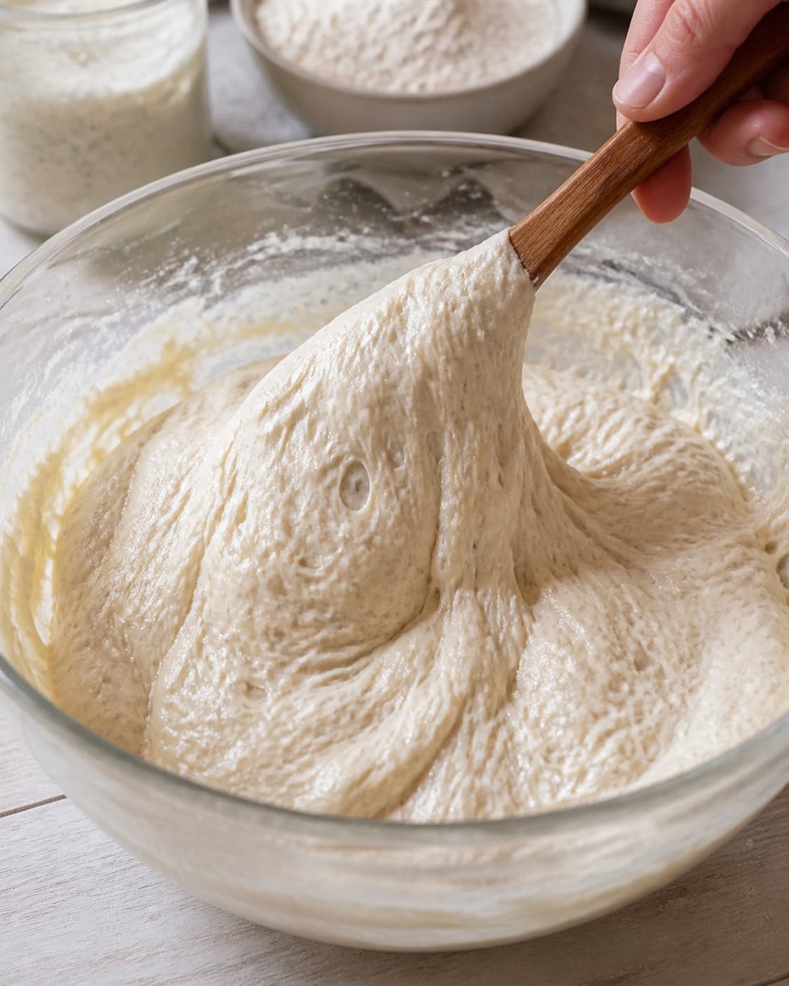 Close view of the moist dough for grydebrød med surdej being mixed in a bowl with aktiv surdej, hvedemel, lunkent vand, gær under tilberedningen af grydebrød med surdej