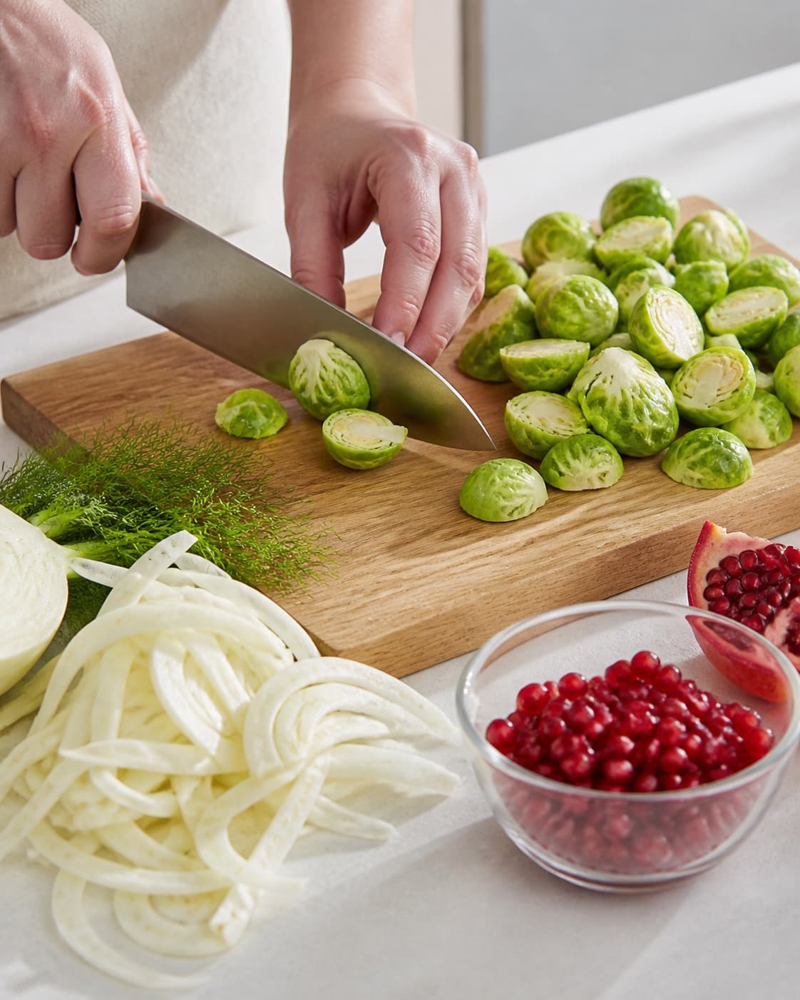 Ingredients for rosenkålssalat med granatæble og fennikel being cut into even pieces under tilberedningen af rosenkålssalat med granatæble og fennikel