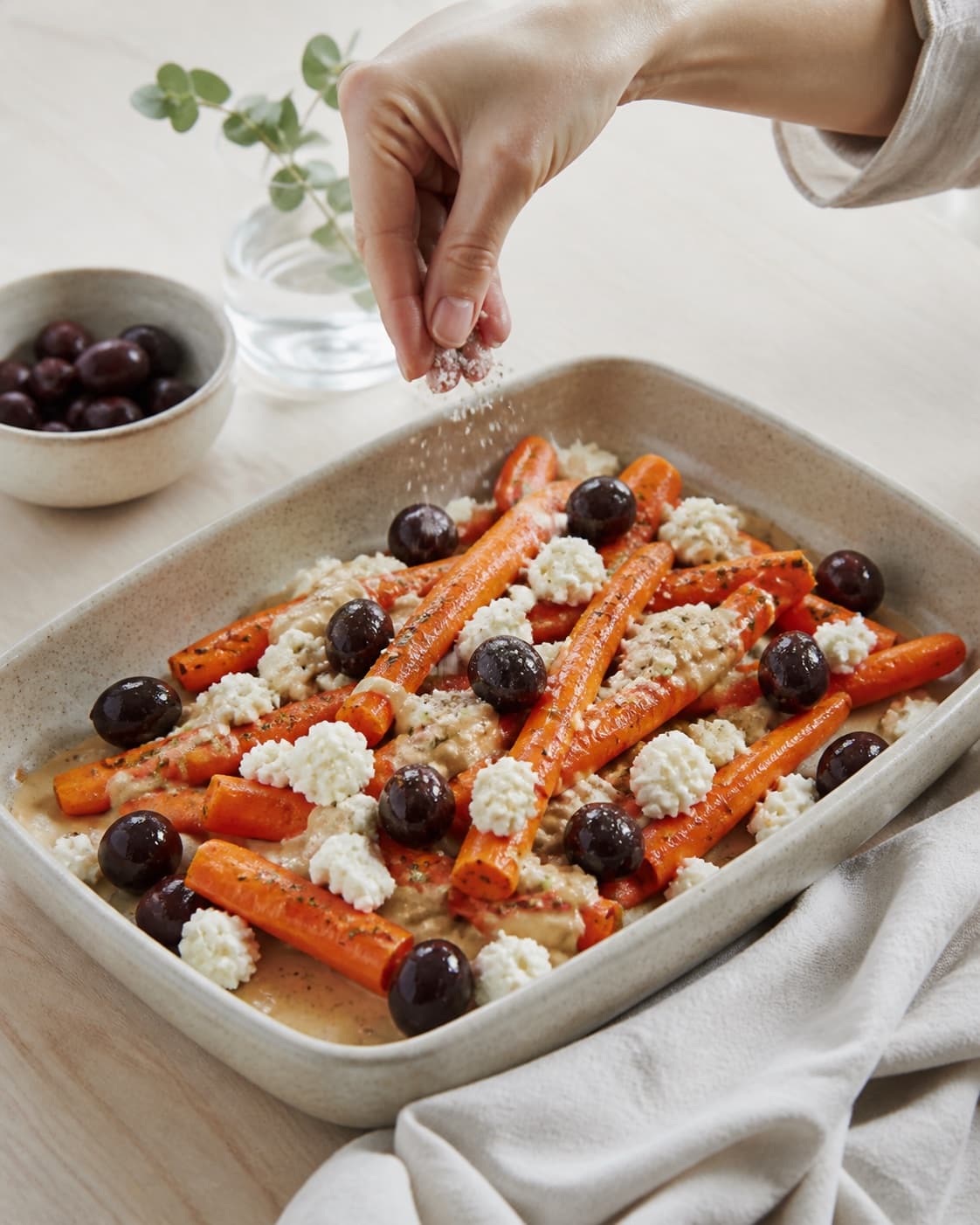 grillede gulerødder med feta, oliven og tahin being evenly seasoned before roasting under tilberedningen af grillede gulerødder med feta, oliven og tahin