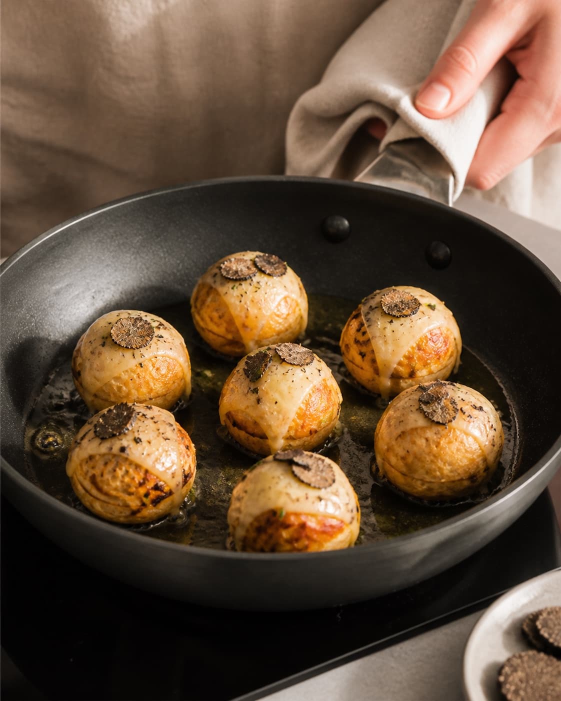 salte æbleskiver med brie og trøffel frying to an even golden crust in a pan under tilberedningen af salte æbleskiver med brie og trøffel