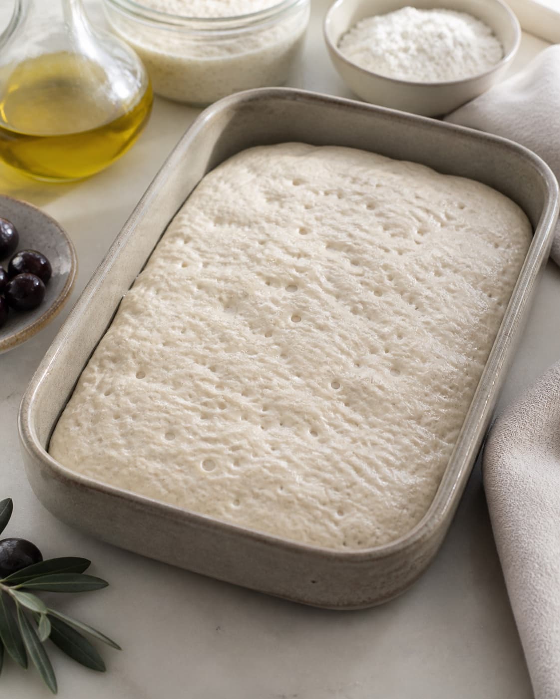 Proofed airy dough for foccacia med surdej og oliven with visible fermentation bubbles under tilberedningen af foccacia med surdej og oliven