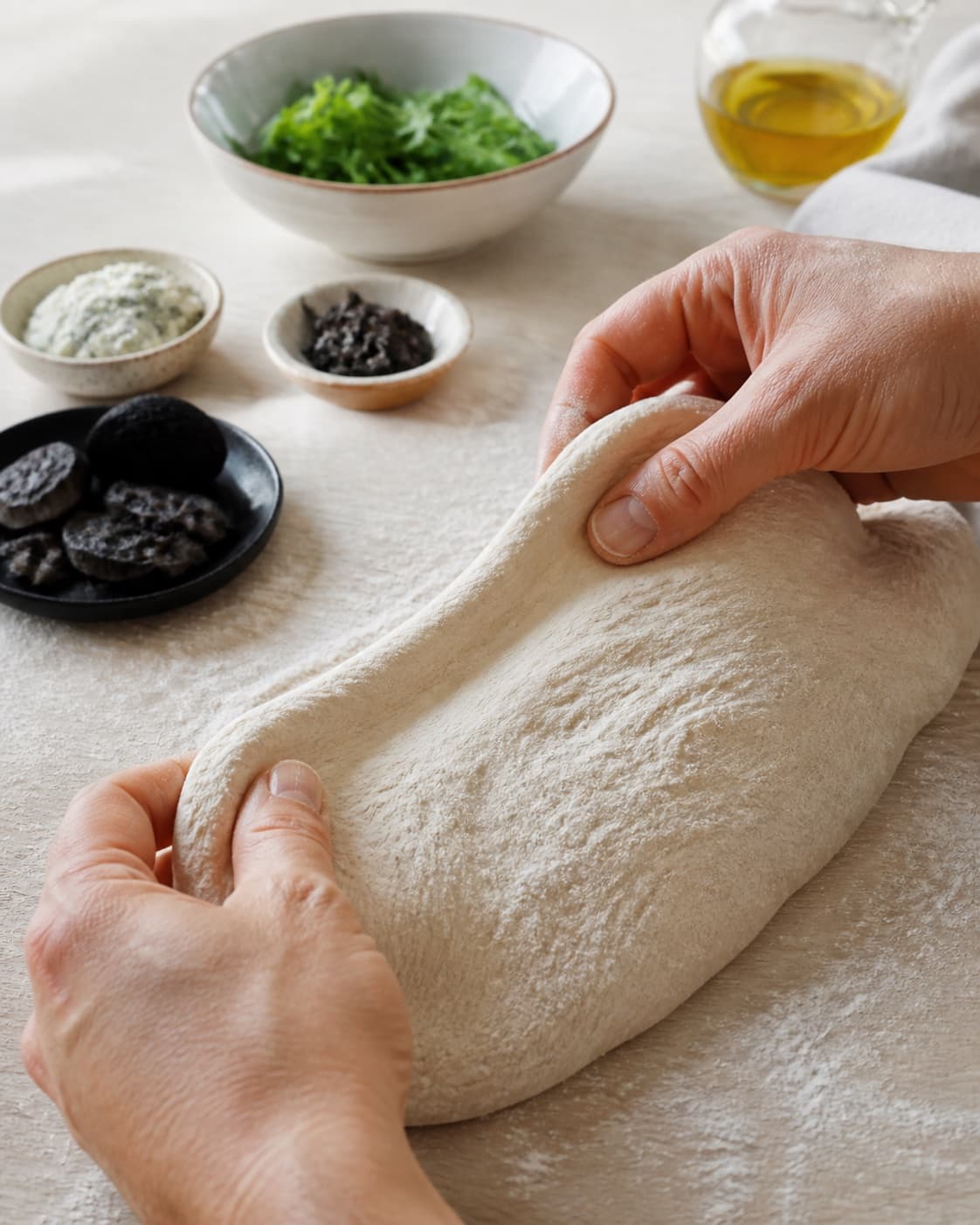 Hands gently folding elastic dough for pizza med gorgonzola, chorizo og trøffel under tilberedningen af pizza med gorgonzola, chorizo og trøffel