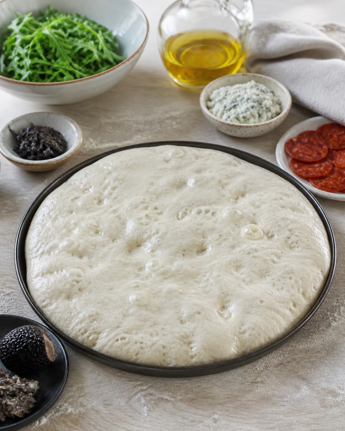 Proofed airy dough for pizza med gorgonzola, chorizo og trøffel with visible fermentation bubbles under tilberedningen af pizza med gorgonzola, chorizo og trøffel