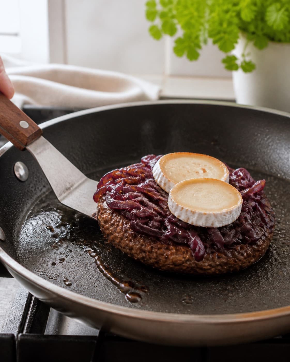 burger med gedeost og karamelliserede rødløg frying to an even golden crust in a pan under tilberedningen af burger med gedeost og karamelliserede rødløg