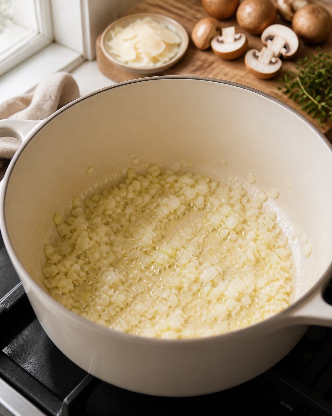 Aromatic base for svamperisotto med revet parmesan gently cooking in a pot under tilberedningen af svamperisotto med revet parmesan
