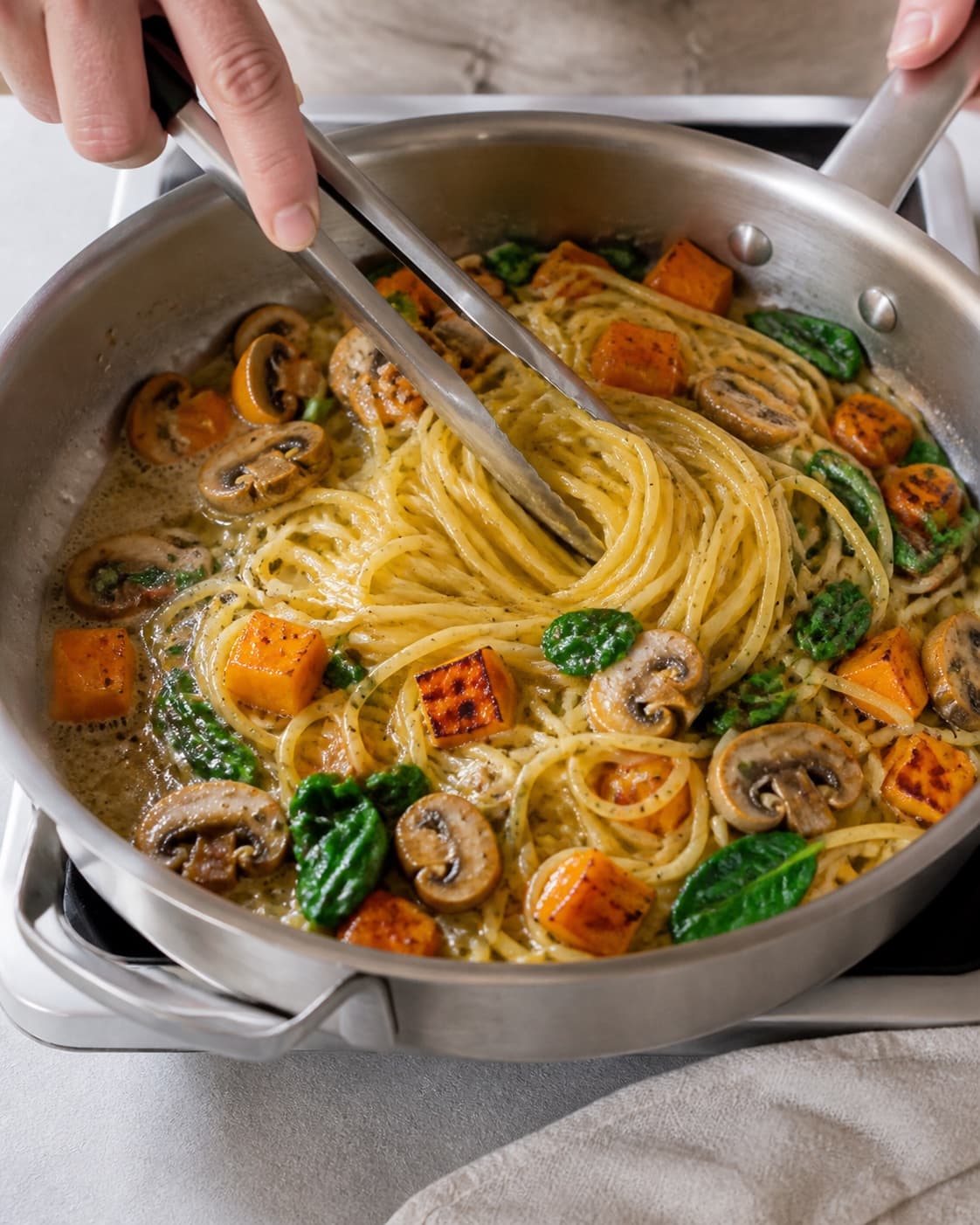 pasta med græskar, svampe og spinat being emulsified in a broad pan under tilberedningen af pasta med græskar, svampe og spinat