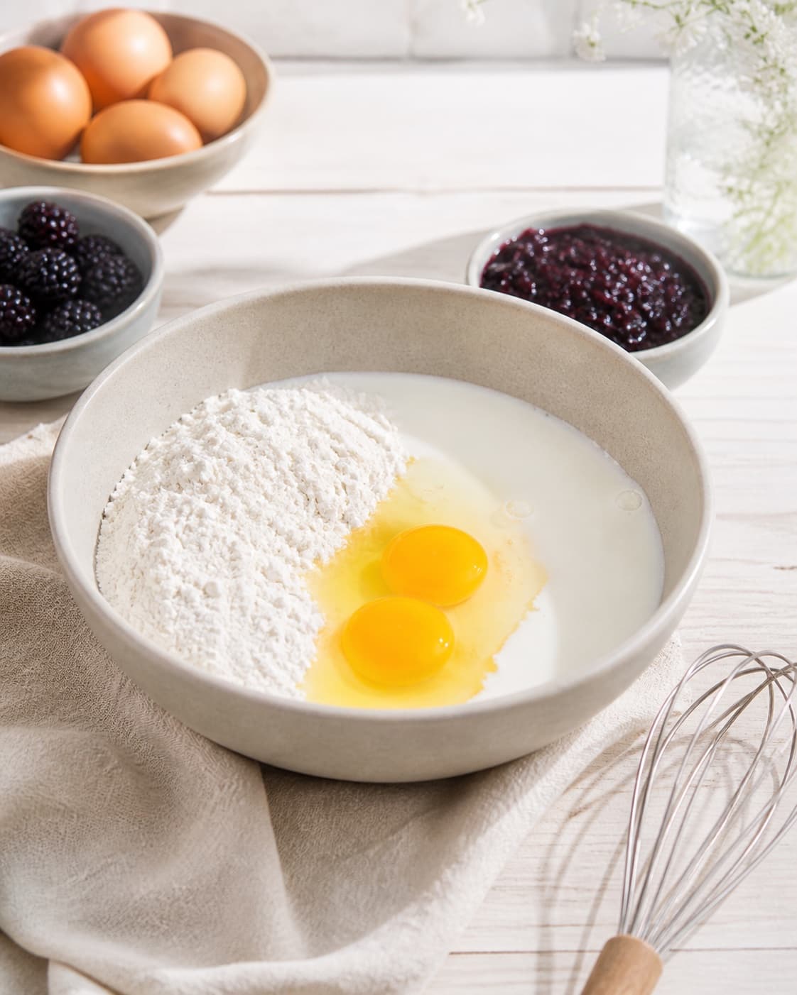 Prepared mixture for amerikanske pandekager med brombærkompot with brombær, æg, hvedemel, mælk under tilberedningen af amerikanske pandekager med brombærkompot