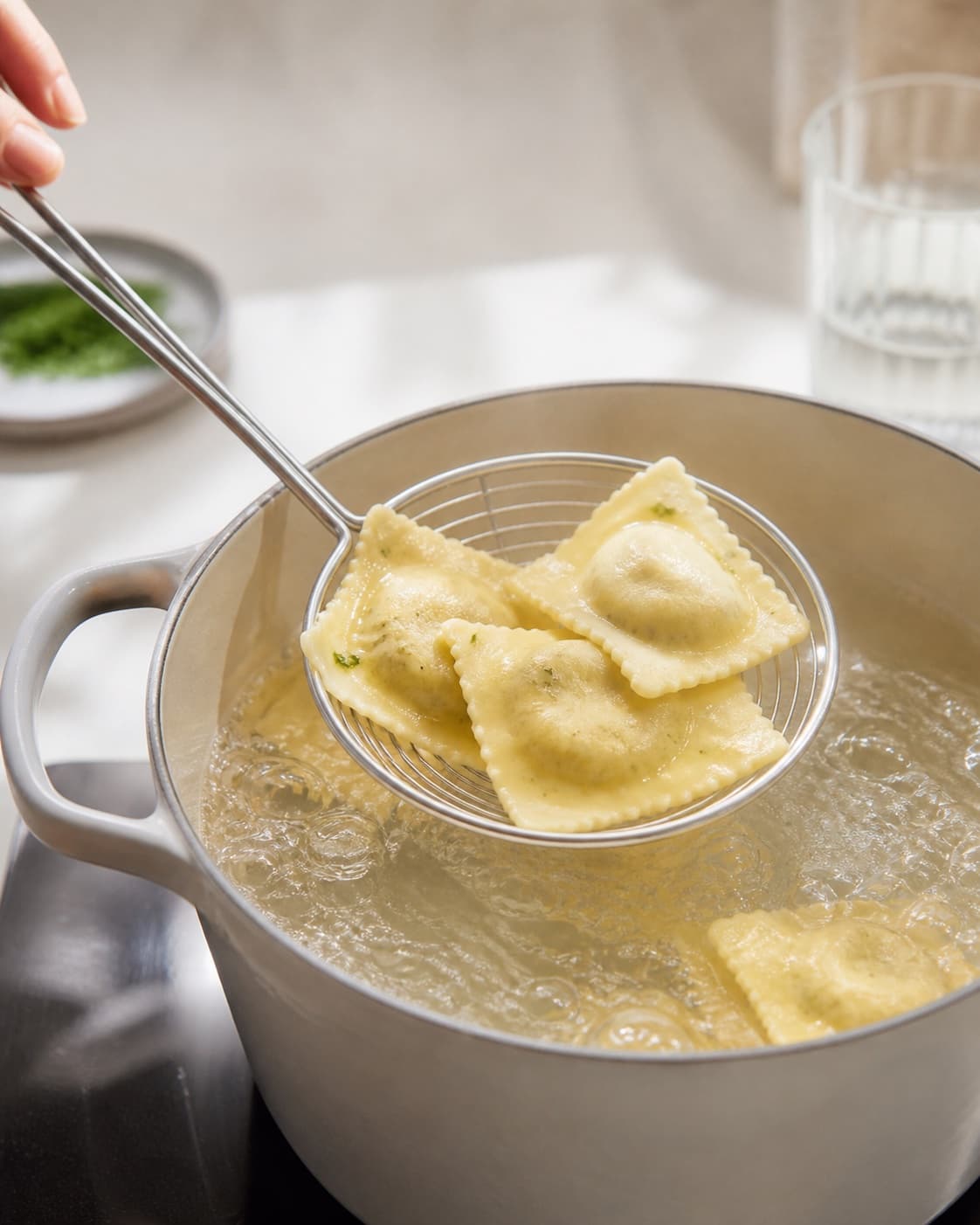 Pasta for strandkrabbebisque med ravioli being lifted from boiling water under tilberedningen af strandkrabbebisque med ravioli