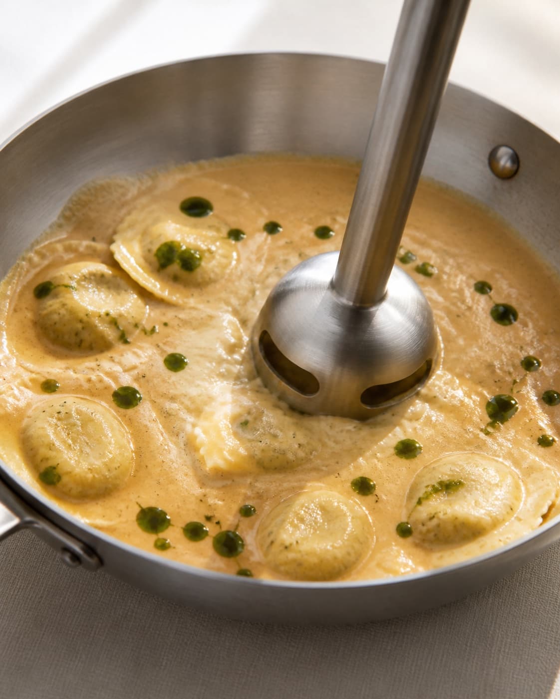 strandkrabbebisque med ravioli being emulsified in a broad pan under tilberedningen af strandkrabbebisque med ravioli