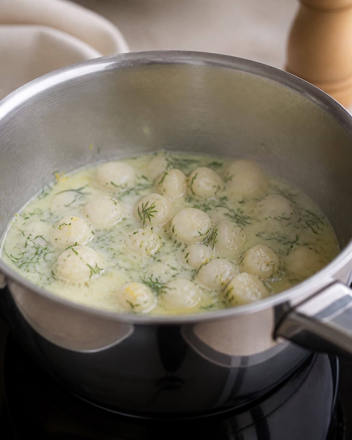 Aromatic base for farserede rødspætter med fyld af kammusling gently cooking in a pot under tilberedningen af farserede rødspætter med fyld af kammusling