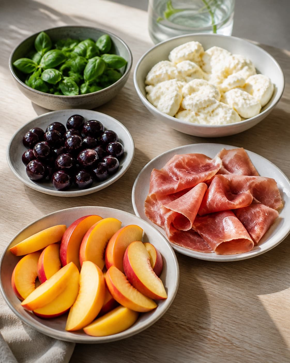 Clean prepared ingredients for salat med mozzarella, fersken og serrano with mozzarella, modne ferskner, serranoskinke, frisk basilikum under tilberedningen af salat med mozzarella, fersken og serrano