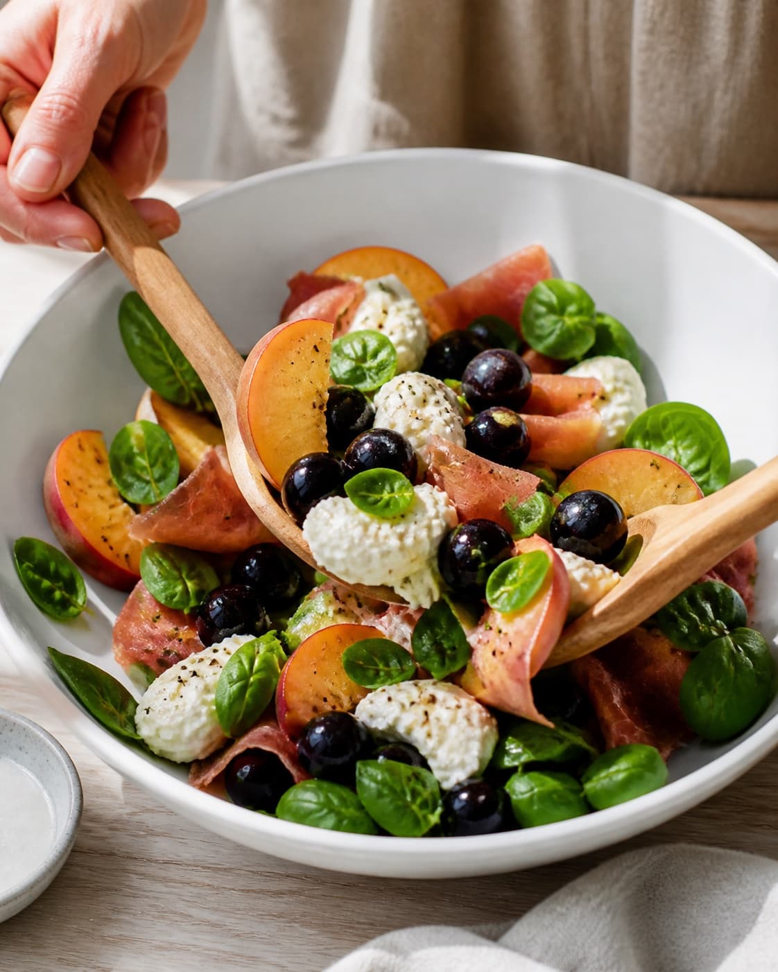 salat med mozzarella, fersken og serrano being gently combined without crushing the ingredients under tilberedningen af salat med mozzarella, fersken og serrano