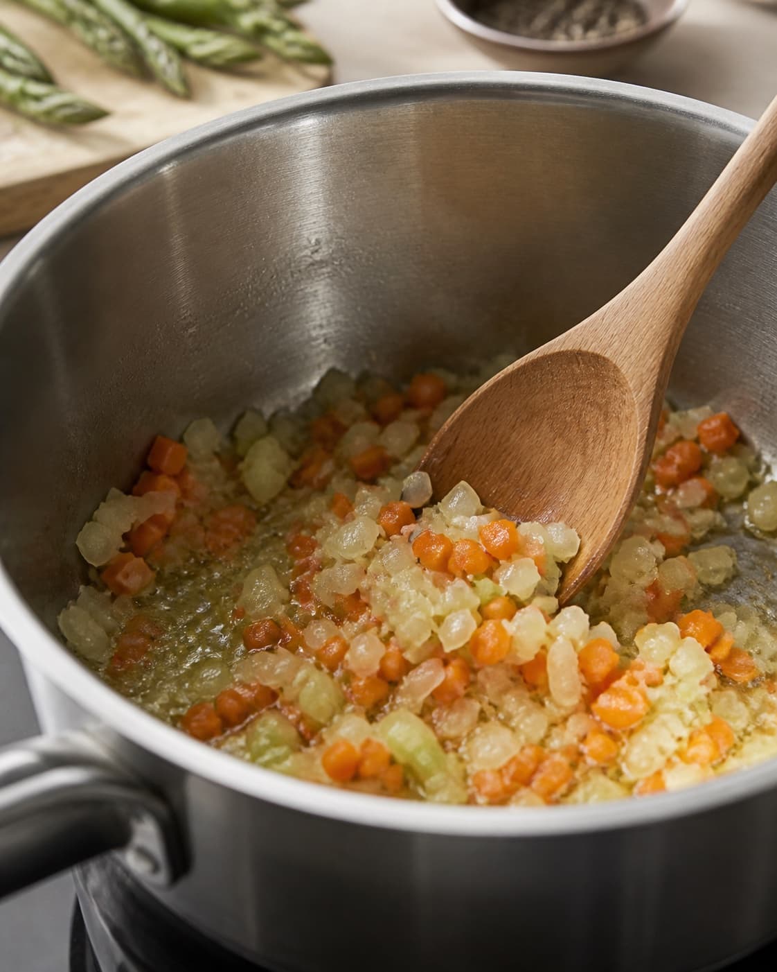 Aromatic base for perlebygotto med asparges og gulerødder gently cooking in a pot under tilberedningen af perlebygotto med asparges og gulerødder