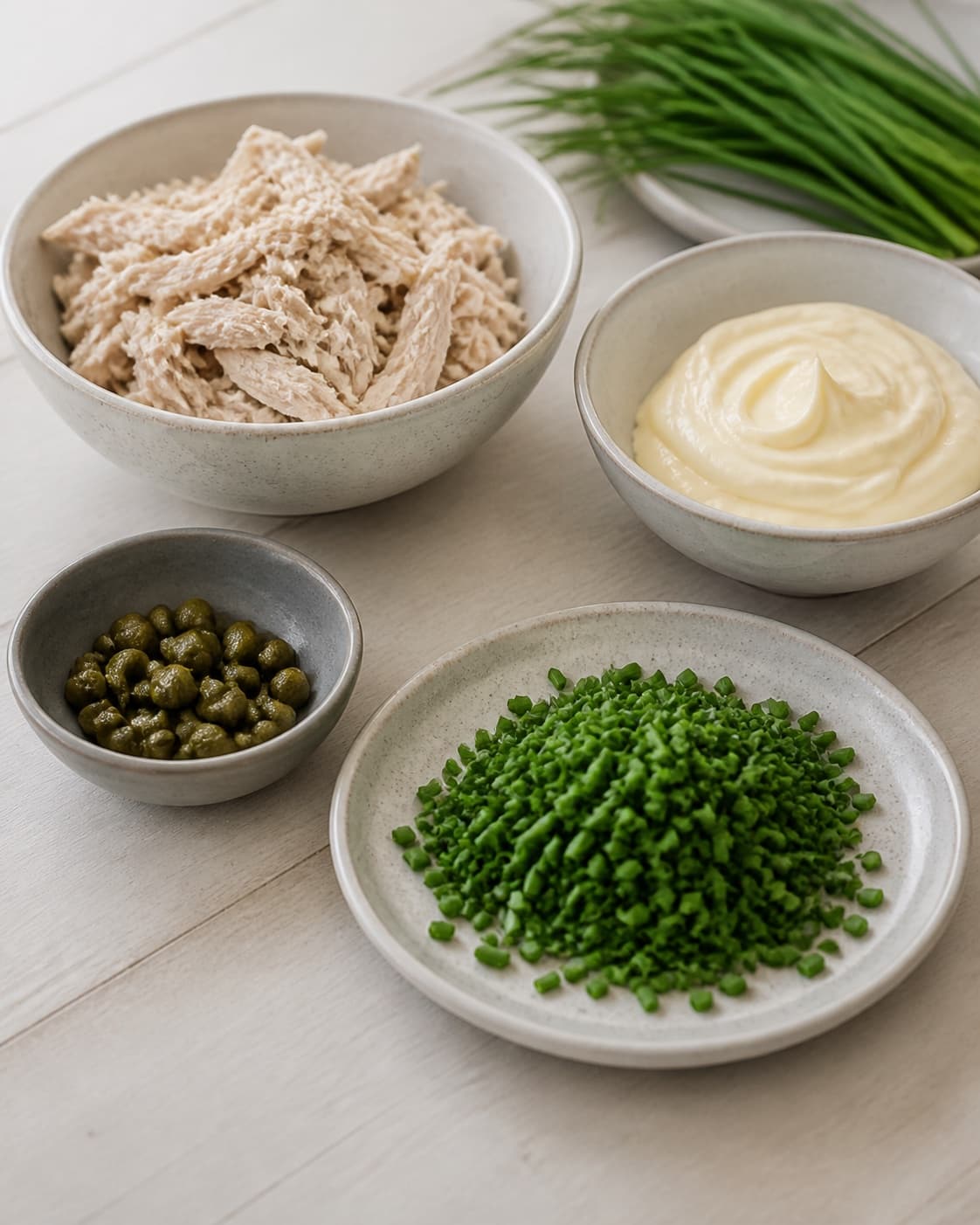 Clean prepared ingredients for kyllingesalat med purløg og kapers with kyllingebryst, mayonnaise, frisk purløg, kapers under tilberedningen af kyllingesalat med purløg og kapers