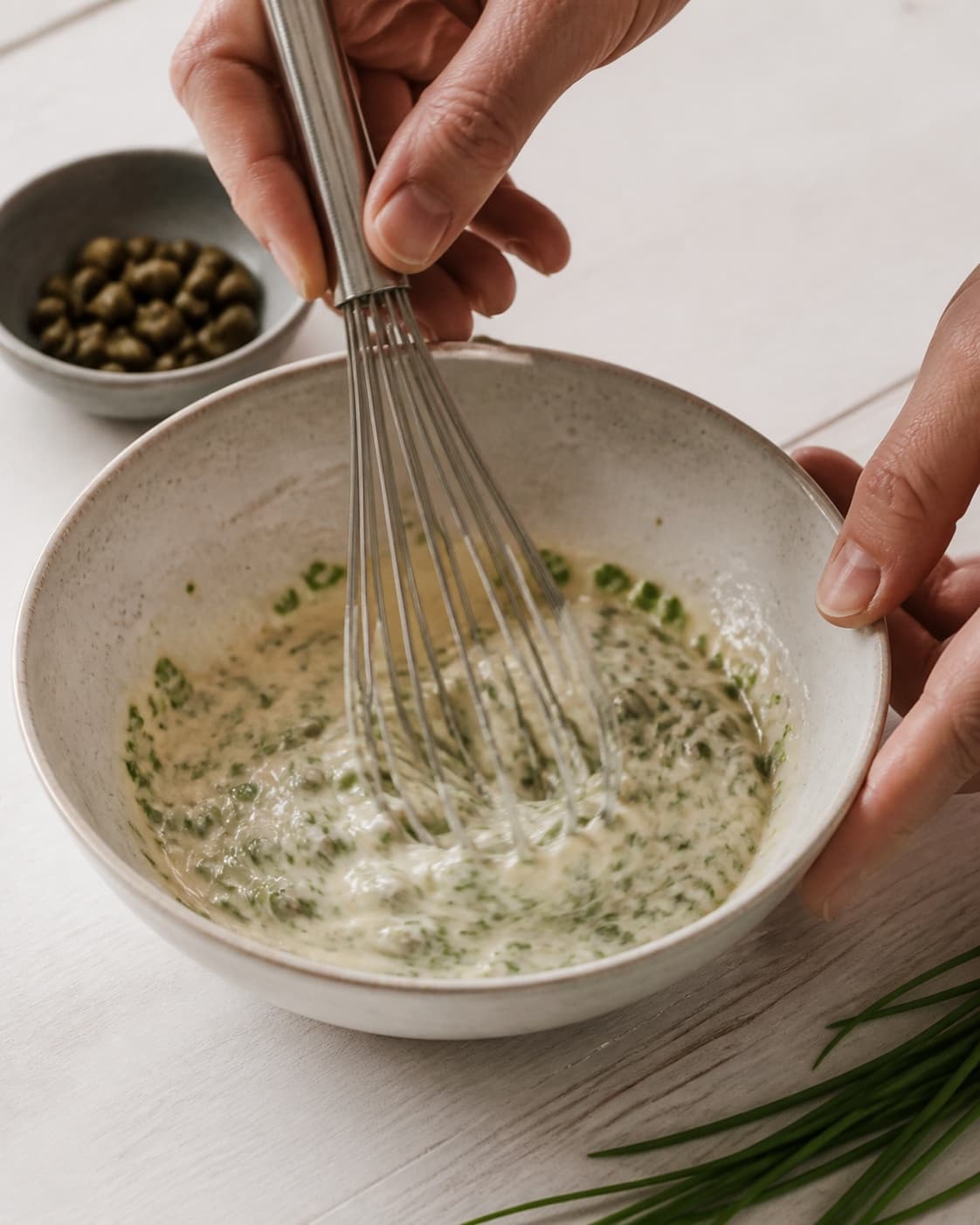 Dressing for kyllingesalat med purløg og kapers being whisked until glossy under tilberedningen af kyllingesalat med purløg og kapers