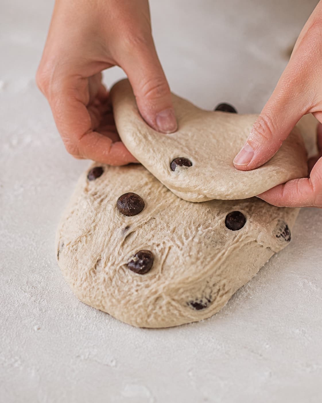 Hands gently folding elastic dough for chokoladeboller med surdej under tilberedningen af chokoladeboller med surdej