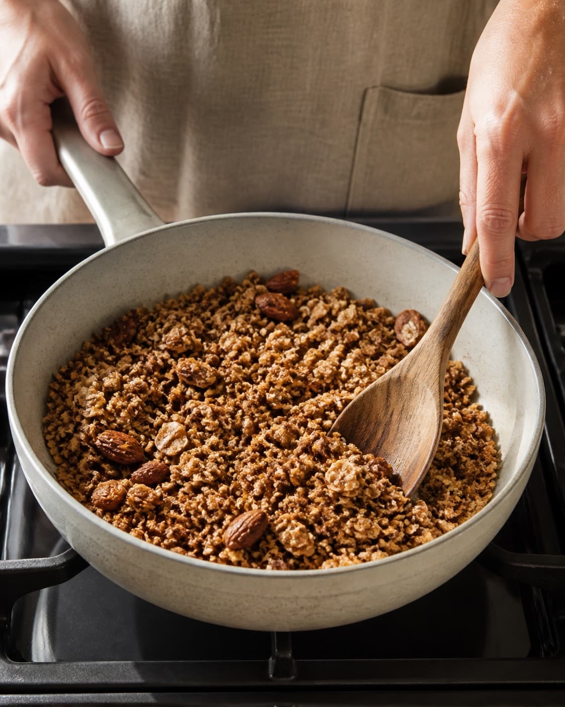The texture of sprød hjemmelavet müsli på panden being adjusted in the pot under tilberedningen af sprød hjemmelavet müsli på panden