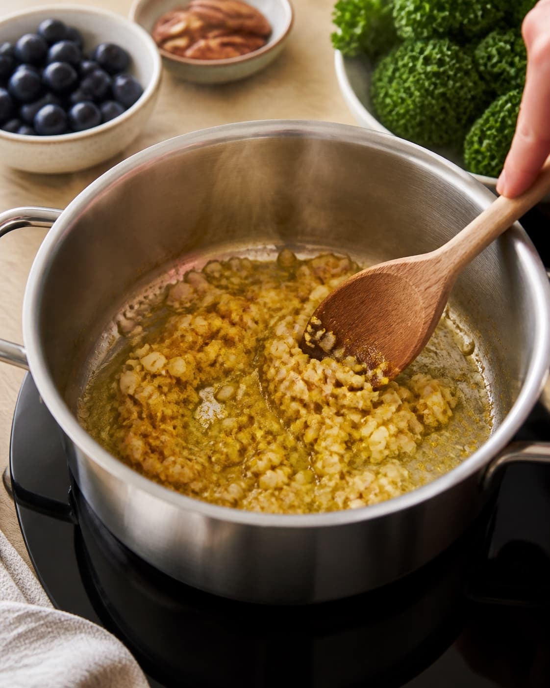 Aromatic base for cremet rissalat med grønkål og karrydressing gently cooking in a pot under tilberedningen af cremet rissalat med grønkål og karrydressing