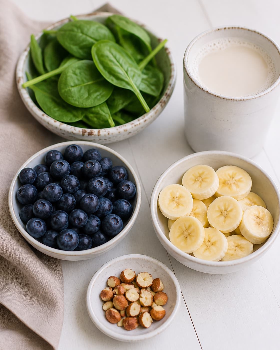 Clean prepared ingredients for smoothie bowl med blåbær og spinat with blåbær, frisk spinat, modne bananer, havredrik under tilberedningen af smoothie bowl med blåbær og spinat