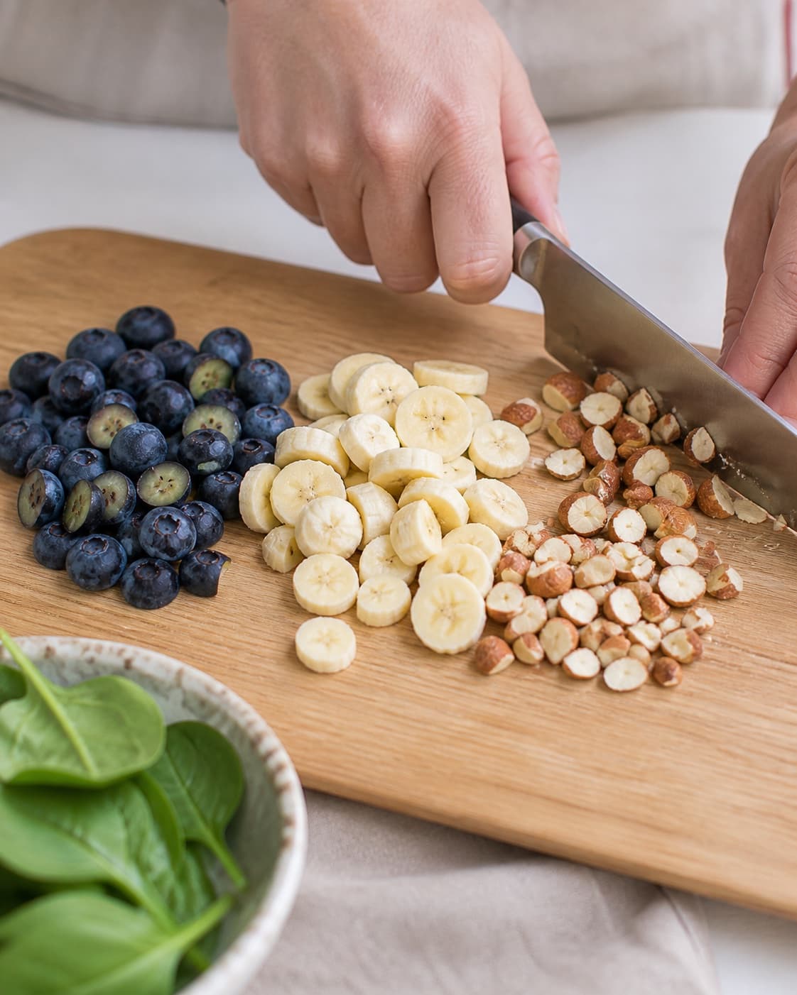 Ingredients for smoothie bowl med blåbær og spinat being cut into even pieces under tilberedningen af smoothie bowl med blåbær og spinat